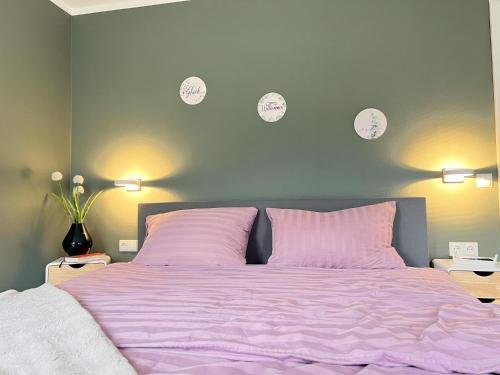 a bedroom with a bed with pink sheets and clocks on the wall at Dahmer Strand 1 - LÜTT HUIS in Dahme