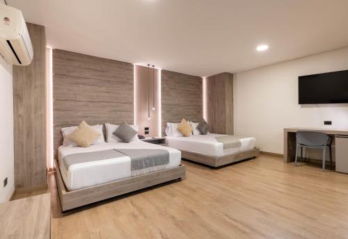 a bedroom with two beds and a flat screen tv at Hotel Time Oclock Medellin in Medellín