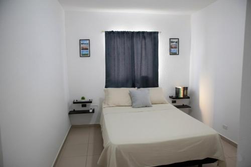 a bedroom with a white bed with a blue curtain at Kirara's House in Chanmico