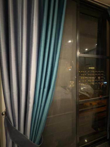 a window with a blue curtain and a city skyline at Royale Rest Suites in Rāmkot