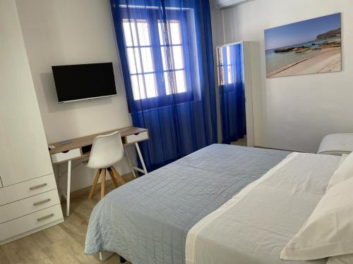 a bedroom with a bed and a desk and a television at Casa dei mulini in Favignana