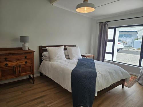 a bedroom with a bed and a dresser and a window at Graatjie in Kleinmond