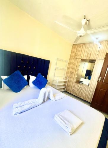 a bedroom with a large white bed with blue pillows at Guest Favorite 1BDR with Washer, Netflix, Parking & Hot Shower 2547,96,065,022 in Mombasa