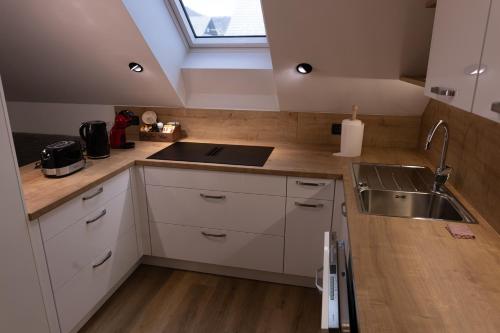 a kitchen with white cabinets and a sink and a window at Mahne Apartment in Kranj