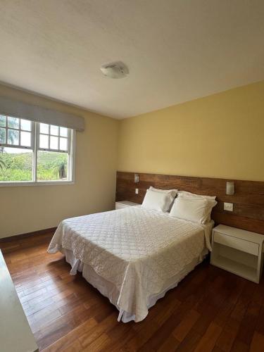 a bedroom with a bed with white sheets and a window at Pousada Vila Leopoldina in Tiradentes