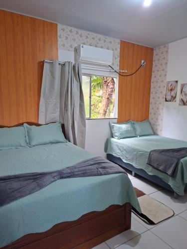 a bedroom with two beds and a window at cantinho da Raq,um quarto SUÍTE com ar condicionado duas camas de casal perto doAeroporto, UEPA, Rodoviaria, magueirao, UFPA,parque ambiental, in Belém