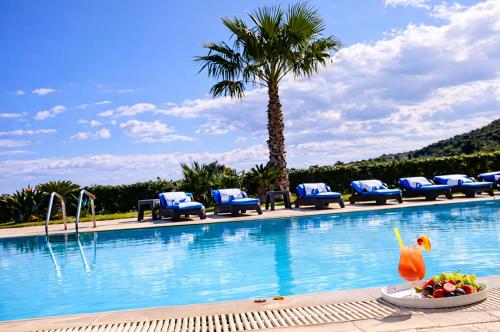 a resort swimming pool with a bowl of fruit and a drink at Bella Villa with Private Pool & Sea View Ideal for Groups in Vaia