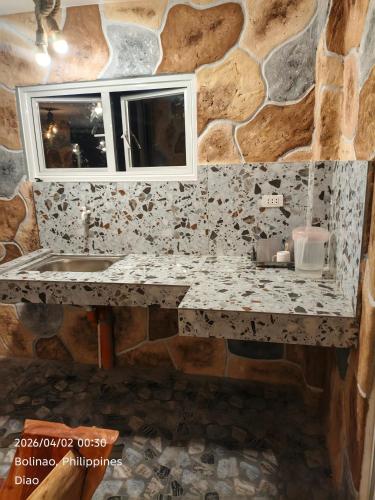 a bathroom with a sink and a stone wall at Ocean View and Beach Access Rustic Stone House in Bolinao