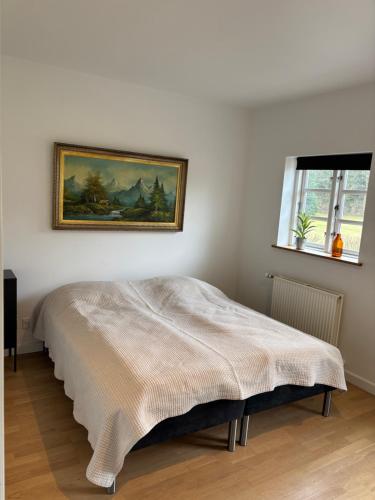 a bed in a room with a painting on the wall at Mosborg Gæstehus in Ulfborg