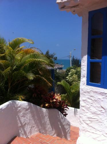 a white building with a blue window and palm trees at Casa KoKopelli in Ballenita