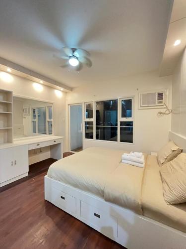 a white bedroom with a bed and a ceiling fan at STAYLUXIA MANILABAYVIEW - FEATURING 1 - 5 BEDROOM SUITES WITH BALCONY POOL BAYVIEWS NETFLIX - Housekeeping Available- in Manila