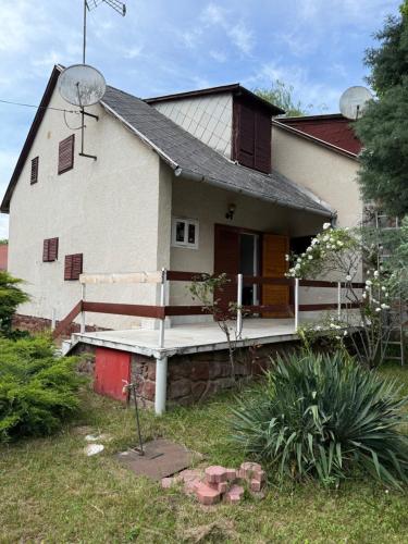 a white house with a porch and a yard at Balatonlak in Ábrahámhegy