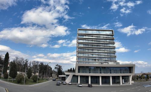 a tall building with cars parked in a parking lot at Naftalan Central Wellness Resort in Naftalan