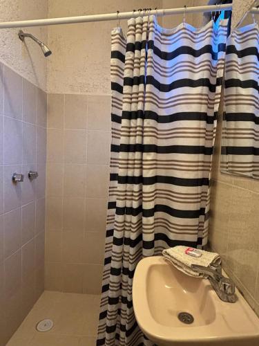 a bathroom with a sink and a shower curtain at Tu casa Oaxaca... in Oaxaca City