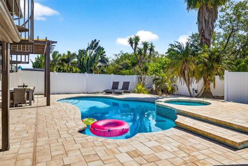 a swimming pool with a pink float in a yard at Heated PoolFoosball,Pac Man Arcade, walk to beach in Clearwater Beach