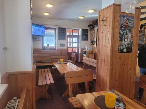 a restaurant with wooden tables and benches in a room at Horská bouda Aldrov in Vítkovice