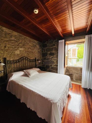 a bedroom with a bed and a stone wall at Casa de Costoia in Santiago de Compostela