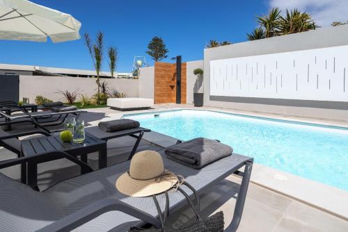 a pool with tables and chairs and a hat on top at AZURE Seaside Residence in Kokkini Khanion