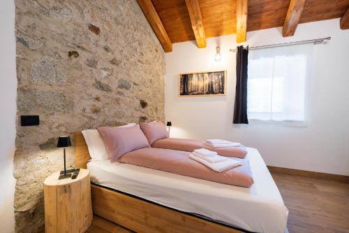 a bed in a room with a stone wall at Country Life Chalet in Tione di Trento