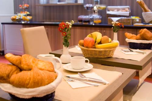 a table with croissants and baskets of bread and fruit at Atlas Hotel Brussels in Brussels