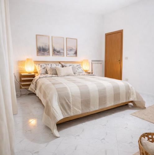 a white bedroom with a large bed and two lamps at Salerno casa con jacuzzi privata e cinema in Salerno