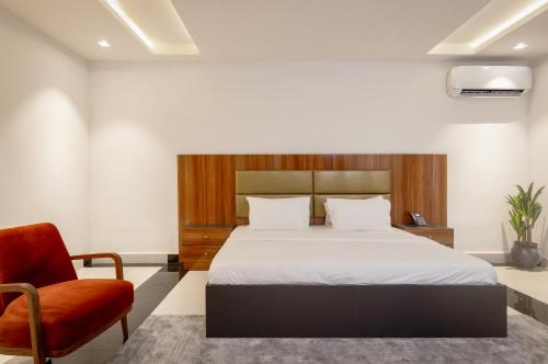 a bedroom with a bed and a red chair at D'Crown Place in Abuja
