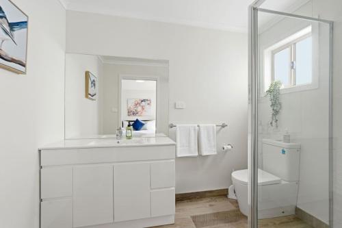 a white bathroom with a sink and a toilet at Tranquil Escape by the Water in Triabunna