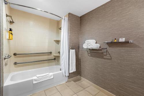 a bathroom with a tub and a shower with towels at Best Western Plus Fresno Airport Hotel in Fresno