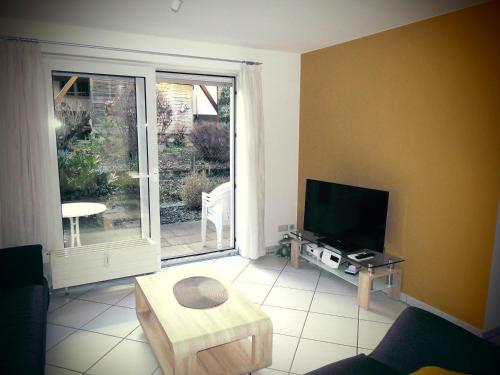 ein Wohnzimmer mit einem Sofa, einem TV und einem Tisch in der Unterkunft Ferienwohnung Wehr in Filderstadt