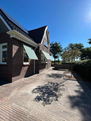 a house with a brick driveway next to a building at Wedderhoeske in Wedde