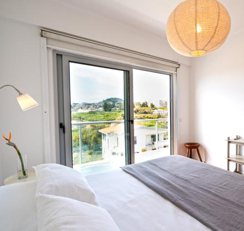 a bedroom with a large window and a bed at Pátio da Achada View Apartment in Funchal
