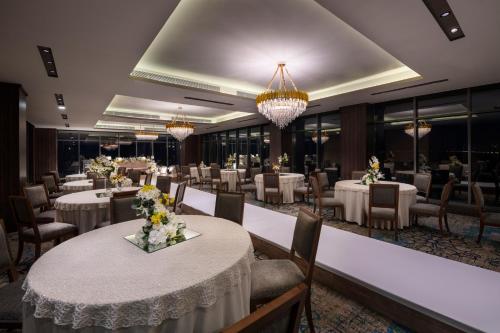 une salle à manger avec des tables, des chaises et des lustres dans l'établissement Waves Hotel, à Umm Lajj