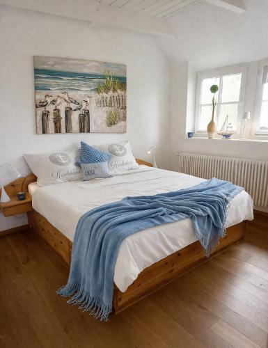 a bedroom with a large bed with a blue blanket on it at Reethus-am-Hafen Reetdachhaus Hafenblick mit Garten und Blick aufs Wasser in Rankwitz