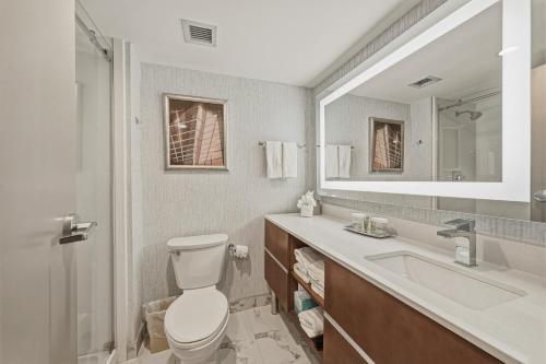 a bathroom with a toilet and a sink and a mirror at Grand Tuscany Hotel in Houston