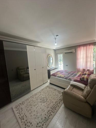 a bedroom with a bed and a couch and a window at Konyaaltı gürsu denize sıfır sahilde full eşyalı lüks daire in Antalya