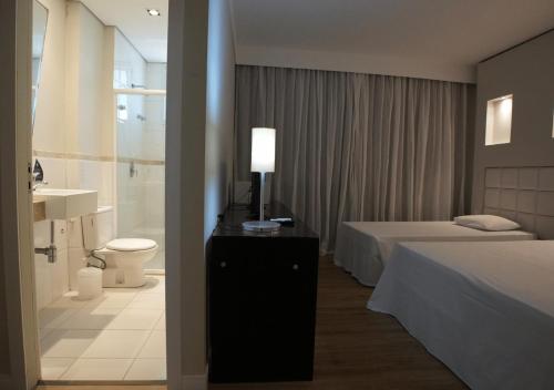 a bedroom with two beds and a bathroom with a toilet at Favorita Golden Hotel e Eventos in São José