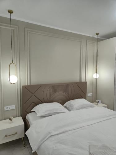 a bedroom with a large white bed and two lamps at Edward Luxury Studio in Slănic-Moldova