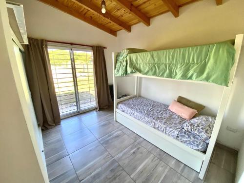 a bedroom with a bunk bed with a window at HastaLaRaíz-LosReartes in Los Reartes