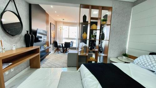 a bedroom with a bed and a living room at Loft sua morada in Capão da Canoa