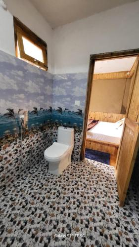 a bathroom with a toilet and a bunk bed at tirthan horizon homestay in Banjār