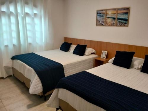 a bedroom with two beds with blue and white sheets at Casa da Dinda 103 in Rio das Ostras