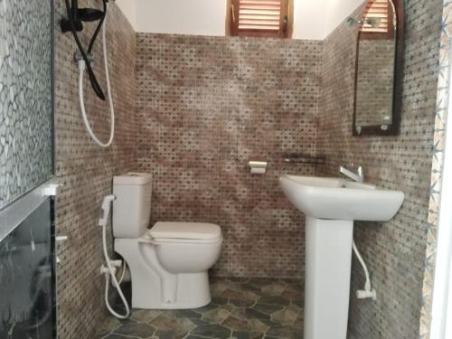a bathroom with a white toilet and a sink at Evara Homestay in Monaragala