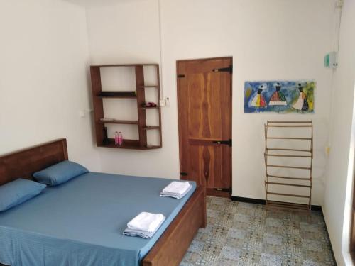 a bedroom with a bed with blue sheets and a door at Evara Homestay in Monaragala