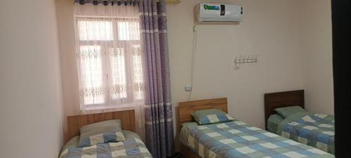 two twin beds in a room with a window at Bro Hostel Angor in Termiz