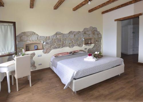 a bedroom with a large bed with a stone wall at b&b il Portico Orgosolo in Orgosolo