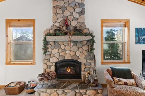 a stone fireplace in a living room with two windows at Cascade Woods in Tahoma