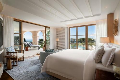 a bedroom with a large bed and a living room at The St. Regis Mardavall Mallorca Resort in Portals Nous