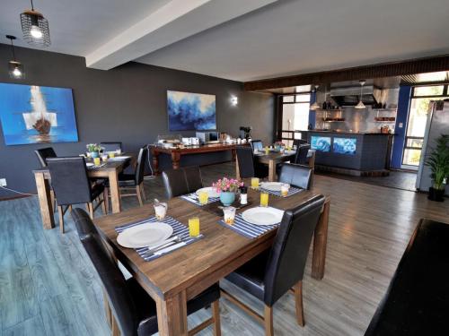 a dining room with a wooden table and chairs at Beachwood Inn Melkbosstrand in Cape Town