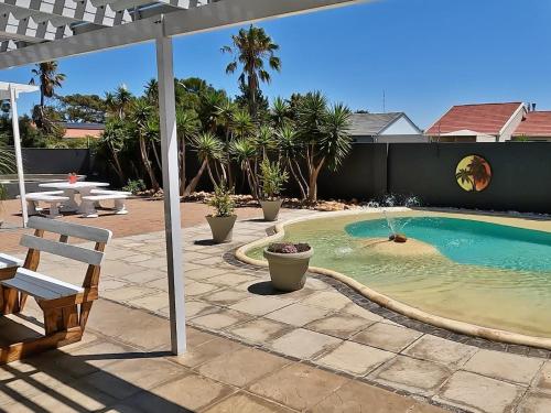 a swimming pool in a backyard with a white umbrella at Beachwood Inn Melkbosstrand in Cape Town