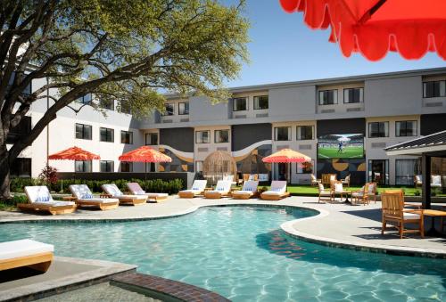 a pool with chairs and umbrellas in front of a hotel at Hotel Dax in Addison